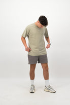 Person wearing a Concept Padel eucalyptus faded tee standing facing forward, styled with grey shorts and trainers against a white background