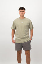 Person wearing a Concept Padel eucalyptus faded tee standing facing forward, styled with grey shorts and trainers against a white background