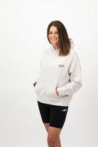 Woman wearing a Concept Padel bone serve hoodie standing side on, paired with black shorts and trainers against a white background