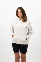 Woman wearing a Concept Padel bone serve hoodie standing facing forward, styled with black shorts and trainers against a white background