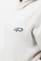 Close‑up of the Concept Padel logo on the bone serve hoodie worn by a woman against a white background