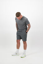 Person wearing Concept Padel shadow performance shorts standing side on, paired with grey tee and trainers against a white background