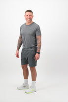 Person wearing Concept Padel shadow performance shorts standing side on, paired with grey tee and trainers against a white background