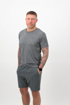 Person wearing Concept Padel shadow performance shorts standing facing forward, styled with grey tee and trainers against a white background