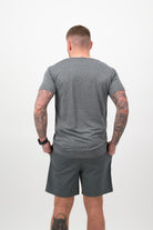 Person wearing a Concept Padel graphite performance tee standing with back to camera showing the clean back silhouette, styled with dark shorts and trainers against a white background