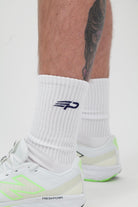 Close up of white Concept Padel everyday socks with blue logo and white trainers