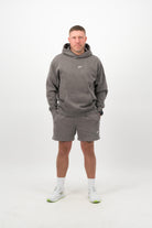 Person wearing a Concept Padel grey faded hoodie standing facing forward, styled with grey shorts and trainers against a white background