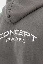 Close‑up of the embroidered Concept Padel logo on the grey faded hoodie worn against a white background