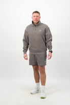 Person wearing a Concept Padel grey faded 1/4 zip sweatshirt standing facing forward, styled with grey shorts and trainers against a white background