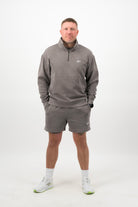 Person wearing a Concept Padel grey faded 1/4 zip sweatshirt standing facing forward, styled with grey shorts and trainers against a white background