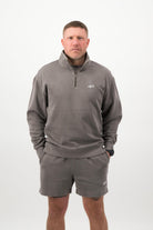 Person wearing a Concept Padel grey faded 1/4 zip sweatshirt standing facing forward, styled with grey shorts and trainers against a white background