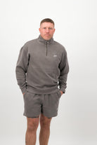 Person wearing a Concept Padel grey faded 1/4 zip sweatshirt standing facing forward, styled with grey shorts and trainers against a white background