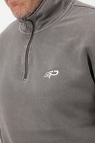 Close‑up of the Concept Padel logo on the grey faded 1/4 zip sweatshirt worn against a white background