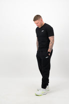 Person wearing a Concept Padel black rebound tee standing side on, paired with black joggers and trainers against a white background