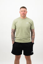 Person wearing a Concept Padel pistachio rebound tee standing facing forward, styled with black shorts and trainers against a white background
