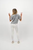 Woman wearing a Concept Padel storm court tee standing with back to camera showing the relaxed silhouette, styled with black shorts and trainers against a white background