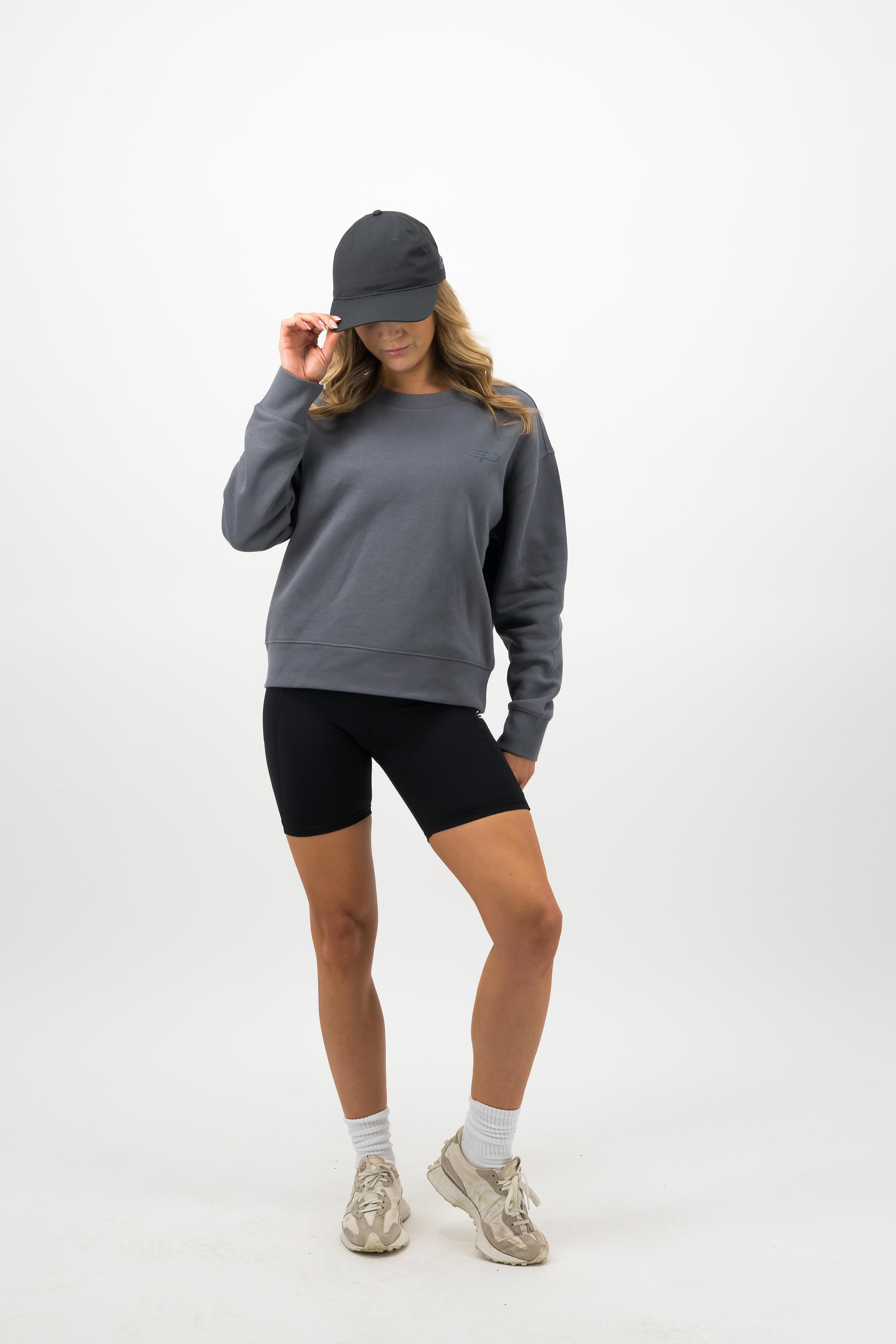 Woman wearing coal Concept Padel cap with grey sweatshirt and shorts