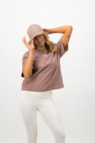 Full outfit featuring woman in hazy pink Concept Padel cap, pink tee and white leggings
