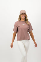 Back view of woman wearing hazy pink Concept Padel cap with white leggings