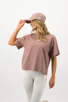 Side view of woman wearing hazy pink Concept Padel cap and relaxed outfit