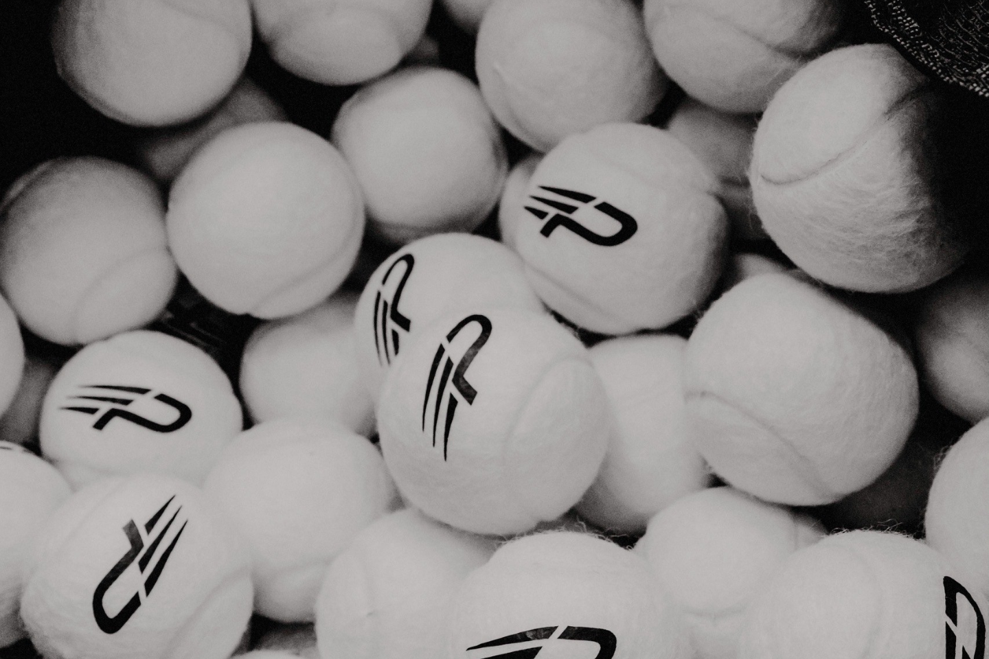 Collection of white tennis balls with a concept padel logo on a black background